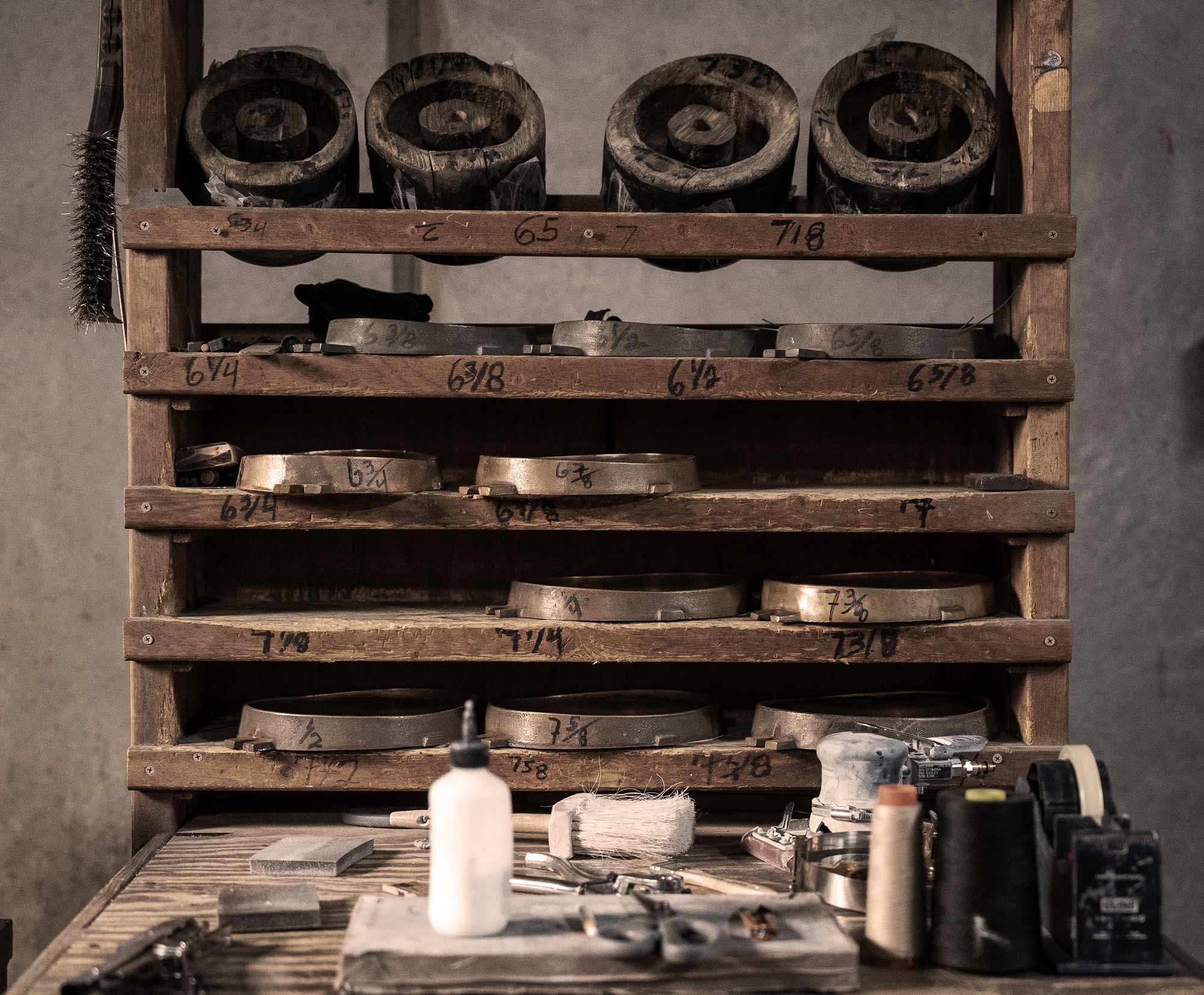 Wooden shelf with metal weights and various tools on a table below.