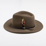 Khaki colored fedora hat with a feather and brown band on a white background