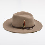 Putty colored fedora hat with a feather and brown band on a white background