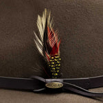 Khaki colored hat with feather decoration with a gold Scala logo and brown band