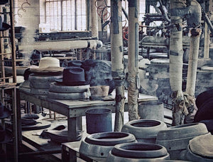 Factory machinery making hats with steam coming out of pipes