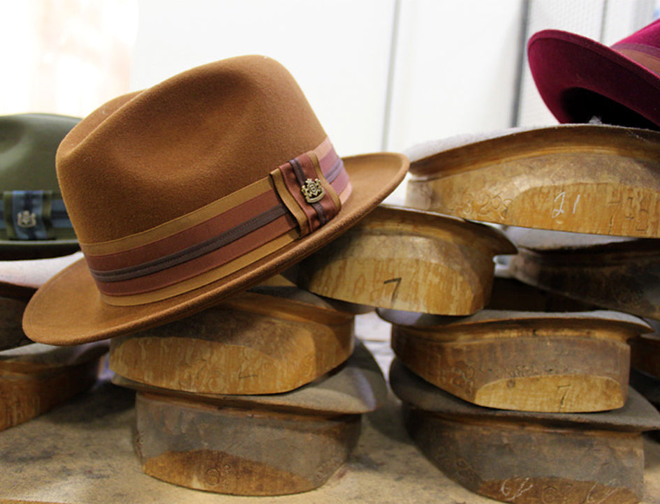 A brown and red hat resting on top of wooden hat blocks