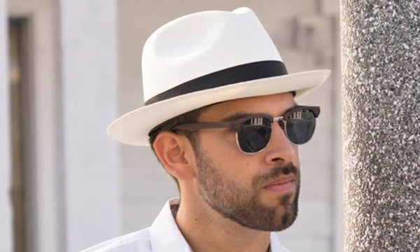 Man wearing a white hat with black band and wite shirt with sunglasses on