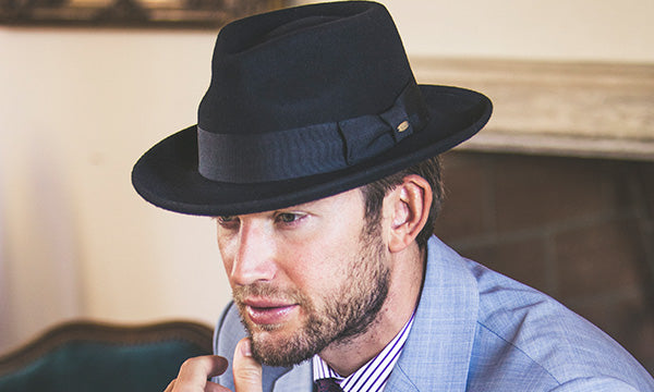Man wearing a black hat and blue suit with a neatly trimmed beard