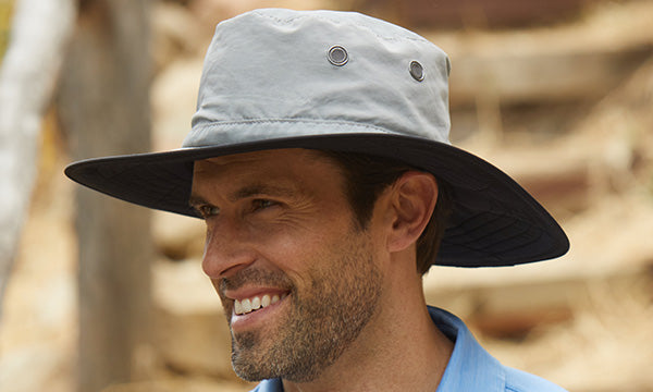 Smiling man wearing a wide brim gray hat and a blue shirt