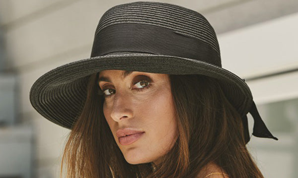 Woman wearing a black hat with a big black band staring off to her left